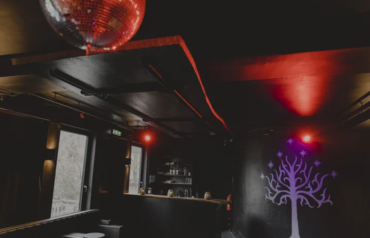 Blick durch den Raum mit Discokugel, Bar und farbigen Lichtern