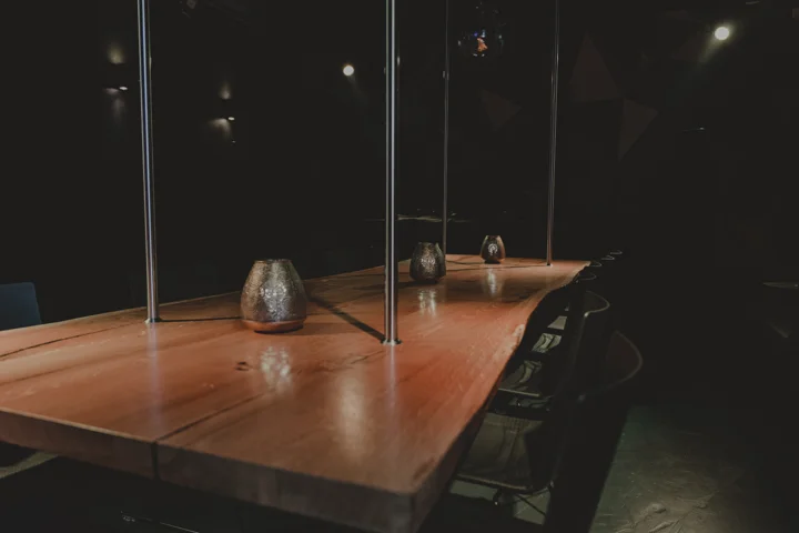 Nahaufnahme der Holztafel mit Kerze und schwarzen Stühlen