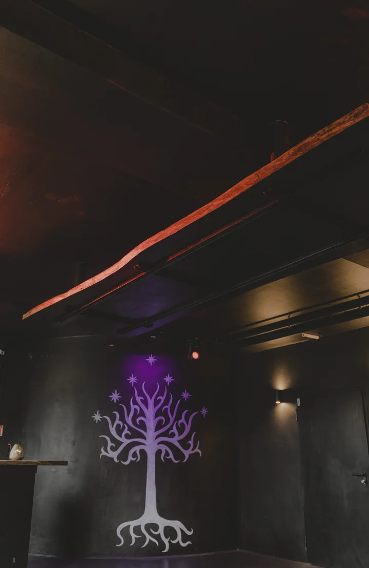 Violett beleuchtetes Baummotiv auf einer dunklen Wand